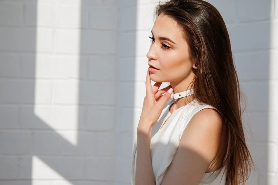 femme en blanc avec un doigt touchant ses lèvres